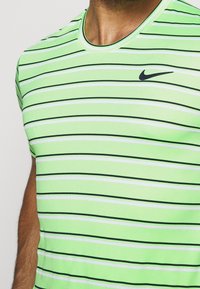 Camiseta de manga corta a rayas verdes y blancas, hecha de un tejido suave. Presenta un logotipo negro de Nike en el pecho.