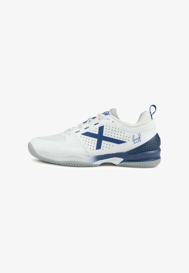 Chaussure de sport blanche et marine avec un logo "X" bleu, une semelle texturée et un détail signature près du talon, vue de côté sur un fond blanc.
