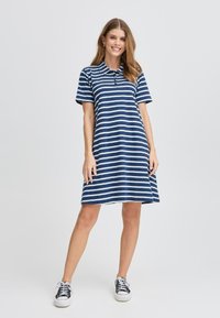 Abito polo a righe navy e bianche realizzato in tessuto morbido, con colletto a bottoni e maniche corte, dalla silhouette a gonna svasata.