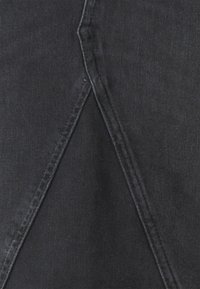 Mustan denim-kankaan, jossa on selkeä viistosti ommeltu sauma, sileä pinta ja hienovarainen haalistuminen tietyillä alueilla.