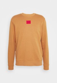 Oranges Sweatshirt mit Rundhalsausschnitt und langen Ärmeln. Verfügt über ein rotes rechteckiges Patch mit dem Text "HUGO" in der Mitte.