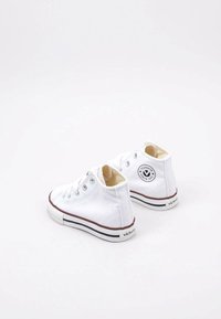 Witte canvas hoge sneakers met een ronde neus, bruine rubberen zool en een zwart rond logo aan de buitenkant. Voorzien van metalen oogjes.