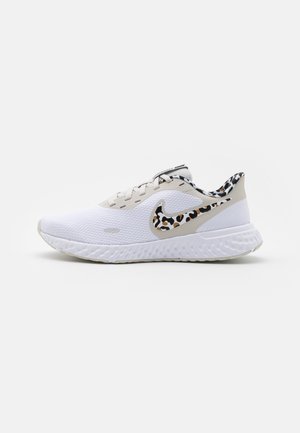 White athletic sneaker with cushioned sole, beige accents, and leopard-print pattern on the Nike swoosh and inner lining.