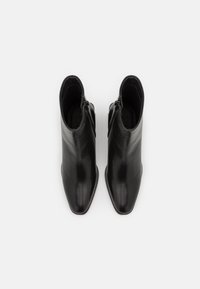 Black leather ankle boots with a pointed toe and smooth finish. Features a side zipper and low stacked heel, suitable for various occasions.