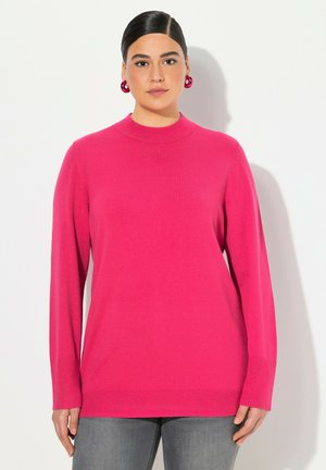 Fuksia neulepusero korkealla kauluksella, pitkät hihat ja textured-helma. Yhdistetty harmaisiin farkkuihin. Sujuva neulekangas; ei näkyviä kuvioita tai metalliosia.