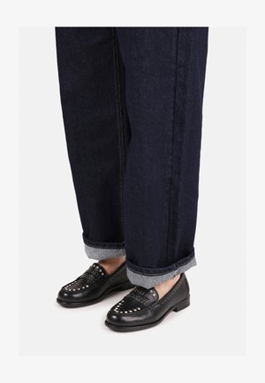 Černé kožené mokasíny se stříbrnými hroty, zaoblená špička, nízký podpatek, nošené s tmavě modrými zkrácenými džínami s kontrastními manžetami.