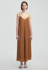 Vestido maxi sin mangas de color marrón con escote en V, que presenta tirantes finos y trenzados. Fabricado en una tela suave, tiene una silueta relajada y fluida.