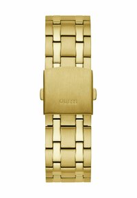 Montre dorée avec un bracelet en maillons métalliques, présentant une finition brossée et une fermeture à boucle, gravée avec le nom de marque "GUESS."