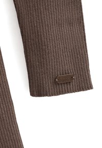 Brun ribbet sweatermanchet med et tekstureret strikkemønster og et lille brunt mærke med teksten "POLO CLUB" fastgjort til kanten.