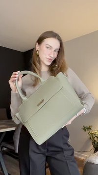 Zöld műbőr kézitáska strukturált kialakítással, felső fogantyúval és elülső hajtókával. Finom fényű és varrási részleteket tartalmaz.