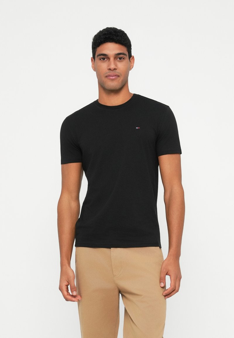 Black cotton t-shirt with short sleeves, crew neck, and a small logo accent on the chest. Smooth texture, fitted design.