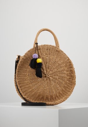 Rund flettet stråhåndtaske med kort håndtag, sort skulderrem og dekorative sorte, lilla og gule kvaster, der hænger fra toppen.