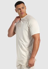 Ljusbeige kortärmad t-shirt med ett strukturerat mönster, rund halsringning och en diskret logotryck på bröstet. Mjuk, andningsbar tyg.