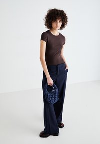 Brown fitted t-shirt, navy wide-leg trousers, and a textured dark blue handbag. Chunky black platform shoes complete the look.
