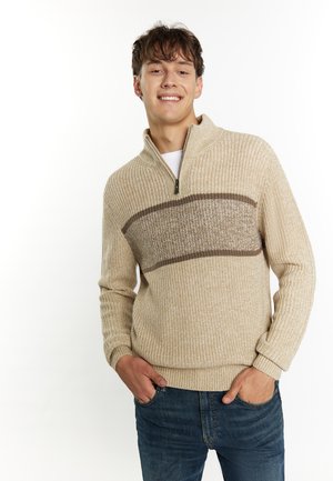 Beige trui met een halve rits kraag, met een textuur gebreid patroon en een bruine horizontale streep over de borst.