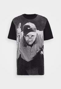 Camiseta negra con un estampado gráfico de una persona con camisa de rayas y gorra, con una superficie texturizada y mangas cortas.