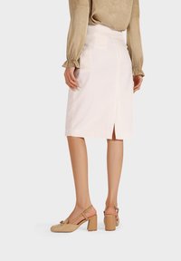 Beige sandály na blokovém podpatku s tkaným textilním svrškem, otevřenou zadní částí, řemínkem kolem kotníku a nízkým střihem. Nosené s bedrěmi v světlé barvě.