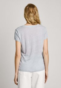 Camiseta de manga corta de color azul claro en tela suave y mezclada. Presenta un escote redondo y un corte relajado, costuras visibles y una textura sutil.