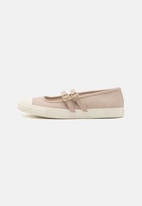 Zapatos mocasines de lona beige con dos correas estrechas y ajustables, y una puntera de goma blanca; suela texturizada para mayor agarre.