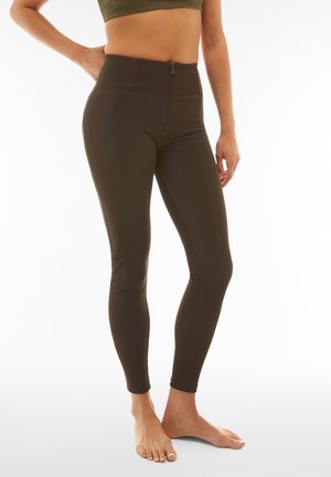 Leggings verde oliva a vita alta, con zip frontale, texture liscia e design aderente che si stringe alla caviglia.