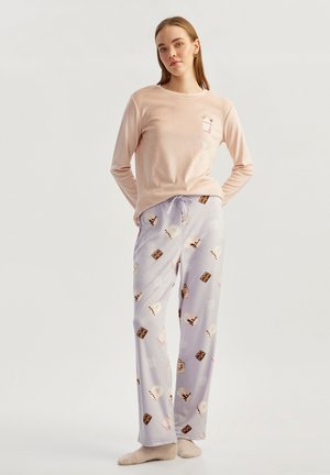 Lichtroze langek mouw top met een kleine graphic, gecombineerd met lila pyjamabroek met dessertpatronen in bruin en wit, gemaakt van zachte stof.