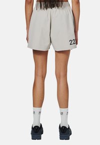 Ljusgrå shorts med elastisk midja, med ett svart nummer "223" på vänstra benet. Matchas med vita strumpor och mörka skor.