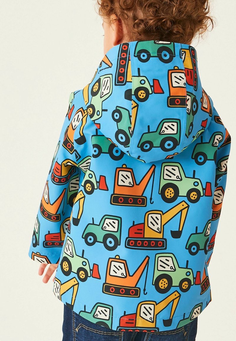 Veste imperméable colorée sur fond bleu, ornée de divers véhicules de chantier de style cartoon. Matériau doux et léger avec une capuche.