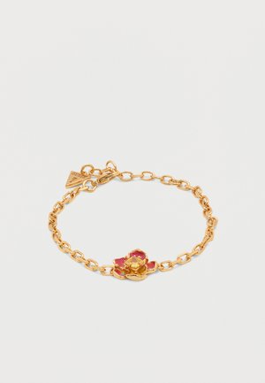 Gouden armband met schakels, versierd met een hanger van een rode en gouden bloem en een klein driehoekig labeltje vlak bij de sluiting, op een witte achtergrond.