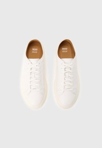 Pair of white leather lace-up sneakers with tan insoles branded "BOSS Ortholite" on a plain light background.