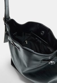 Schwarze Leder-Shopper-Tasche mit weicher Textur, breiter Öffnung, Innentasche und Druckverschluss. Sichtbare Metallakzente.
