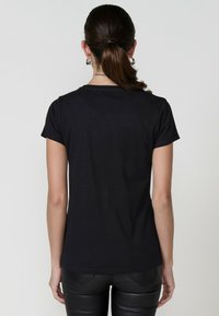 Zwart T-shirt met korte mouwen van zachte katoen, met een klassiek crew neck ontwerp. Gladde textuur met een aansluitende snit en geen zichtbare patronen.