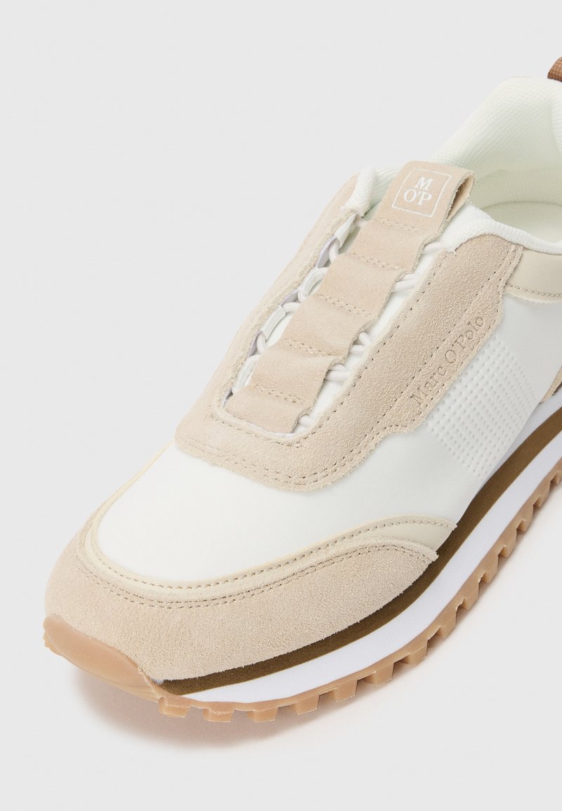 Beżowe i białe sneakersy z zamszowymi akcentami, teksturowaną podeszwą, elastycznymi sznurówkami oraz brandingiem "Marc O’Polo" po boku i na tabliczce języka.