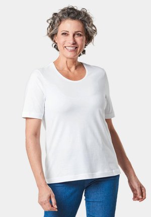 Weißes Baumwoll-T-Shirt mit kurzen Ärmeln, Rundhalsausschnitt und lockerer Passform. Glatte Textur; kombiniert mit blauen Jeans.