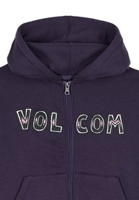 Felpa con zip di colore viola dotata di cappuccio. Presenta il testo "VOL COM" in diversi caratteri e colori. Tessuto morbido con una texture liscia.