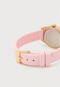 Rosa Silikon-Uhrenarmband mit goldener Schnalle, befestigt an einem goldenen Uhrengehäuse vor weißem Hintergrund.