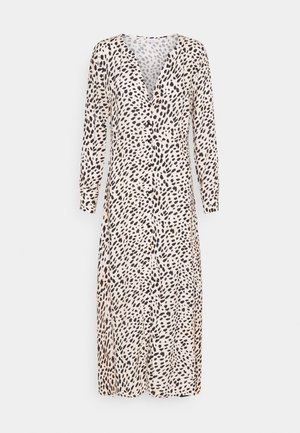 Robe midi à manches longues avec des taches noires irrégulières sur un fond beige et des boutons sur le devant.