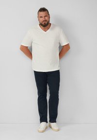 Witte korte mouwen V-hals t-shirt van een lichte stof, gecombineerd met donkerblauwe jeans en witte sneakers, met een casual pasvorm.