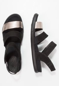 Mustat monihihn sandaalit, joissa on metallinhohtoinen ruusukultainen keskihihna, mokkanahkainen pinta, kumipohja ja säädettävä istuvuus mukavuutta varten.