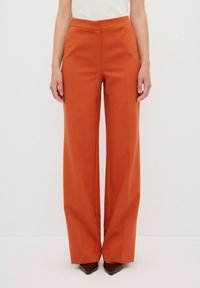 Wijdvallende broek in een levendige oranje kleur, met een gladde textuur, hoge taille en voornaad, gecombineerd met puntige hakken.