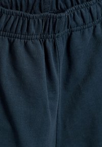 Dunkelblaue Sweatpants aus weichem Stoff; verfügen über einen elastischen Bund mit Raffungen und haben eine glatte Textur ohne Muster oder Akzente.