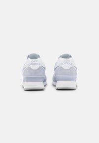 Ljusblå sneakers med mocka och meshmaterial, med en vit hälkappa och silverdetaljer. "New Balance"-logotyp på hälen.