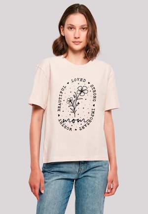 Helles rosa Baumwoll-T-Shirt mit einem schwarzen Blumenmuster und dem Text: "schön, geliebt, stark, wichtig, wertvoll, Mama" in ovaler Anordnung.