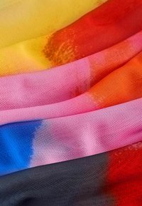 Farverigt mesh-stof i en gradient af gul, pink, rød og blå nuancer, med en let, gennemsigtig struktur og en let strakt vævning.