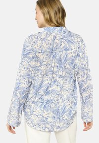 Ziedu raksta krekls krēmkrāsā un zilā, ar garām piedurknēm, apkakli un noapaļotu apakšmalu ar aizmugurēju izgriezumu.