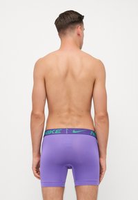 Lilla atletiske boxer shorts med en åndbar, glat tekstur og grønt Nike-logo på taljen, designet til komfort og fleksibilitet.