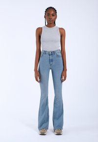 Gray ribbed tank top, high-waisted light blue flared jeans, featuring a button closure and two front pockets, set against a plain white background.