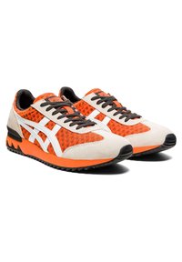 Chaussures de sport en mesh orange avec des accents en daim et en caoutchouc, présentant des bandes blanches, des lacets noirs et une semelle texturée et légère.