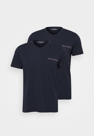 Tummansiniset puuvillapaidat, joissa on V-pääntie, lyhyet hihat ja pieni brodeerattu logo rinnassa. Näytetään kaksi kappaletta.