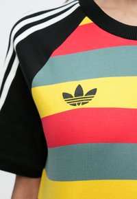 Έγχρωμη ριγέ μπλούζα με κόκκινα, κίτρινα, πράσινα και μαύρα πάνελ; ριμπ λαιμόκοψη; κεντημένο μαύρο λογότυπο Adidas στο μπροστινό μέρος.