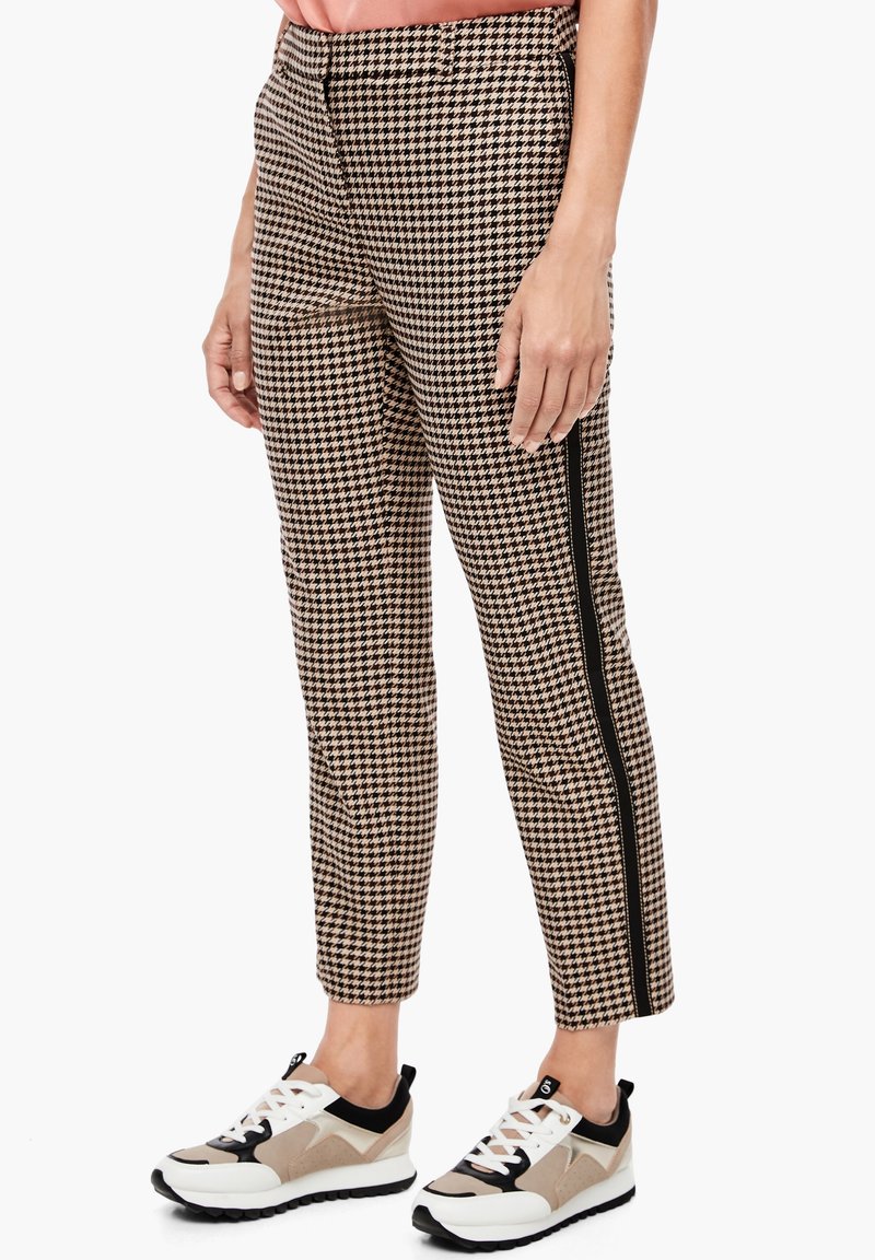 Un pantalon à carreaux dans des nuances de marron et de noir avec une coupe slim, doté de détails de bandes latérales. Associé à des chaussures de sport élégantes.